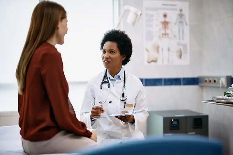 black female doctor talking to a woman during primary care visit