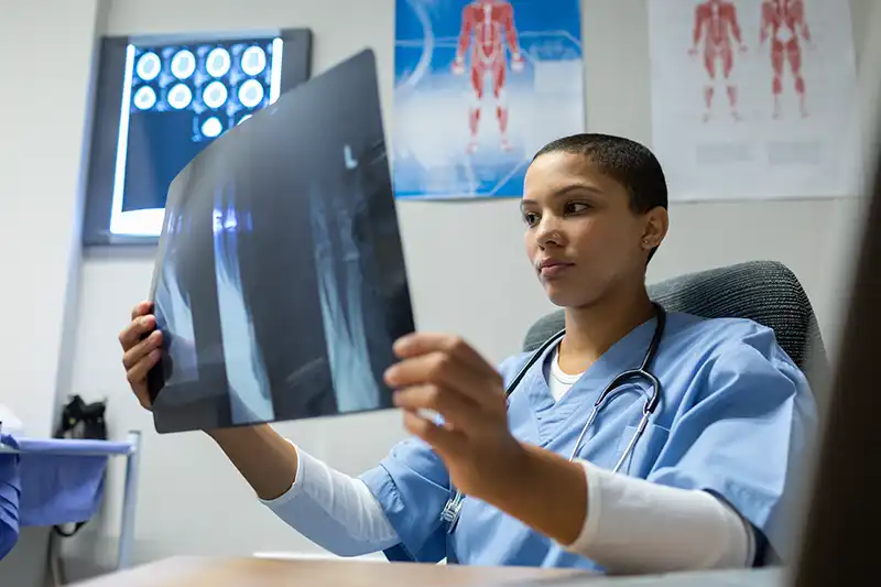 mixed race female doctor examining x ray diagnostic tests